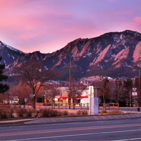 city of Boulder with flatirons and city street at sunset