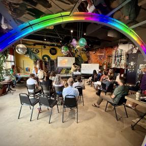 Artists listening to a speaker in Junkyard Social Club, surrounded by a colorful ring of light