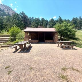 Front-on view of the Bluebell Shelter with picnic tables in front and the First Flatiron visible behind.