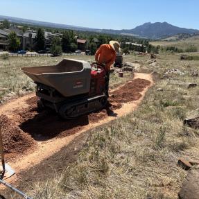 A man pushing a small piece of construction equipment on the North Foothills Trail