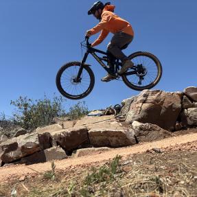 A mountain biker getting some air over a rock feature on the North Foothills Trail.