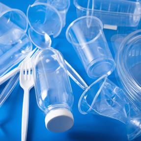 Plastic cups, utensils and containers on a blue background