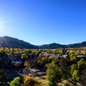 Sun shining behind Boulder mountains, overseeing trees and neighborhoods. 