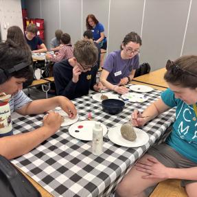 A group of children sitting around a table participating in an activity together. 