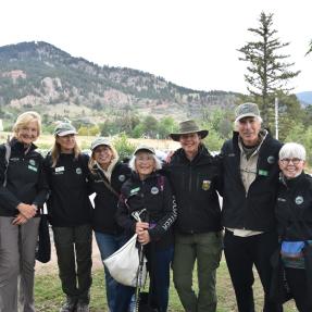 A group of people in black volunteer jackets against the Flatiron Mountains.