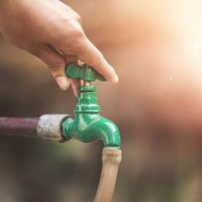 Hand turning off water spigot