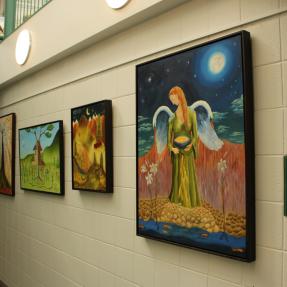 four oil paintings displayed at South Boulder Recreation Center next to a Women's Locker Room sign