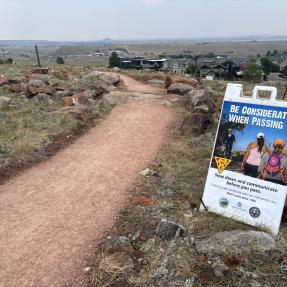 A sign next to North Foothills Trail stating: Be considerate when passing.