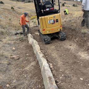 A small yellow construction vehicle working on a trail.