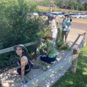 People sitting on a sidewalk next to a garden smiling at the camera.